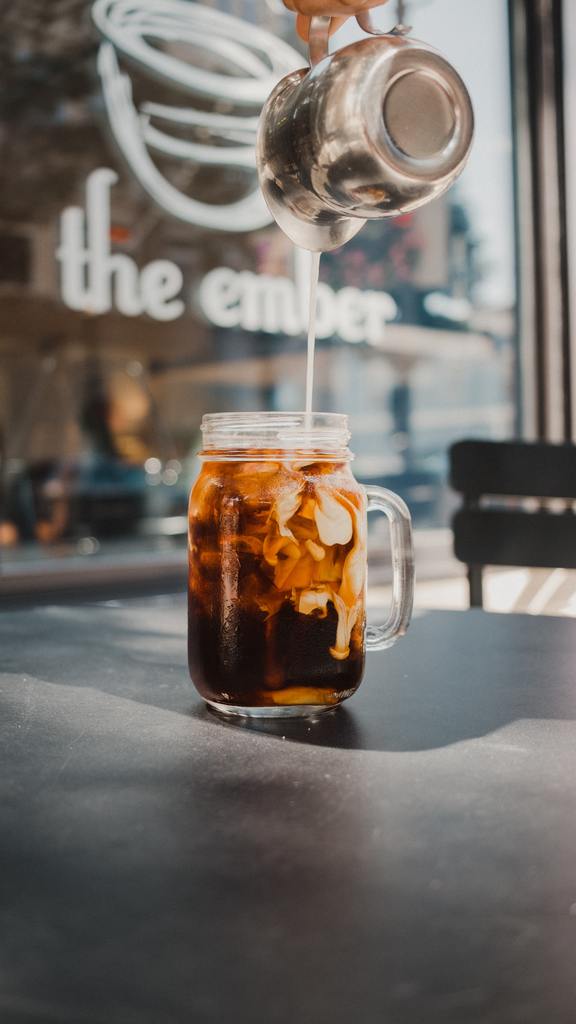 Pouring milk into iced coffee cup